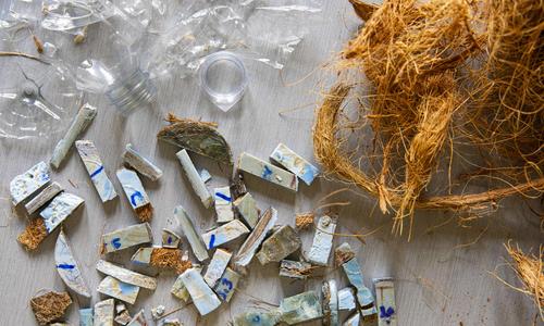 small pieces of plastic bottles, coconut fibers, and the composite roofing material made by combining both, showing an example of innovation for good