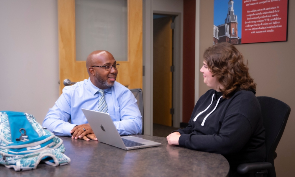 Student success team member helping a student at a table