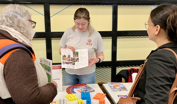 Student exhibiting at the STEM Education Showcase showing talking with two exhibitors.