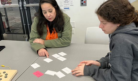 Two people work together at a table with cards at a workshop session