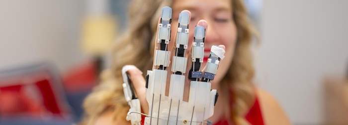 WPI graduate student holding up a robotic hand