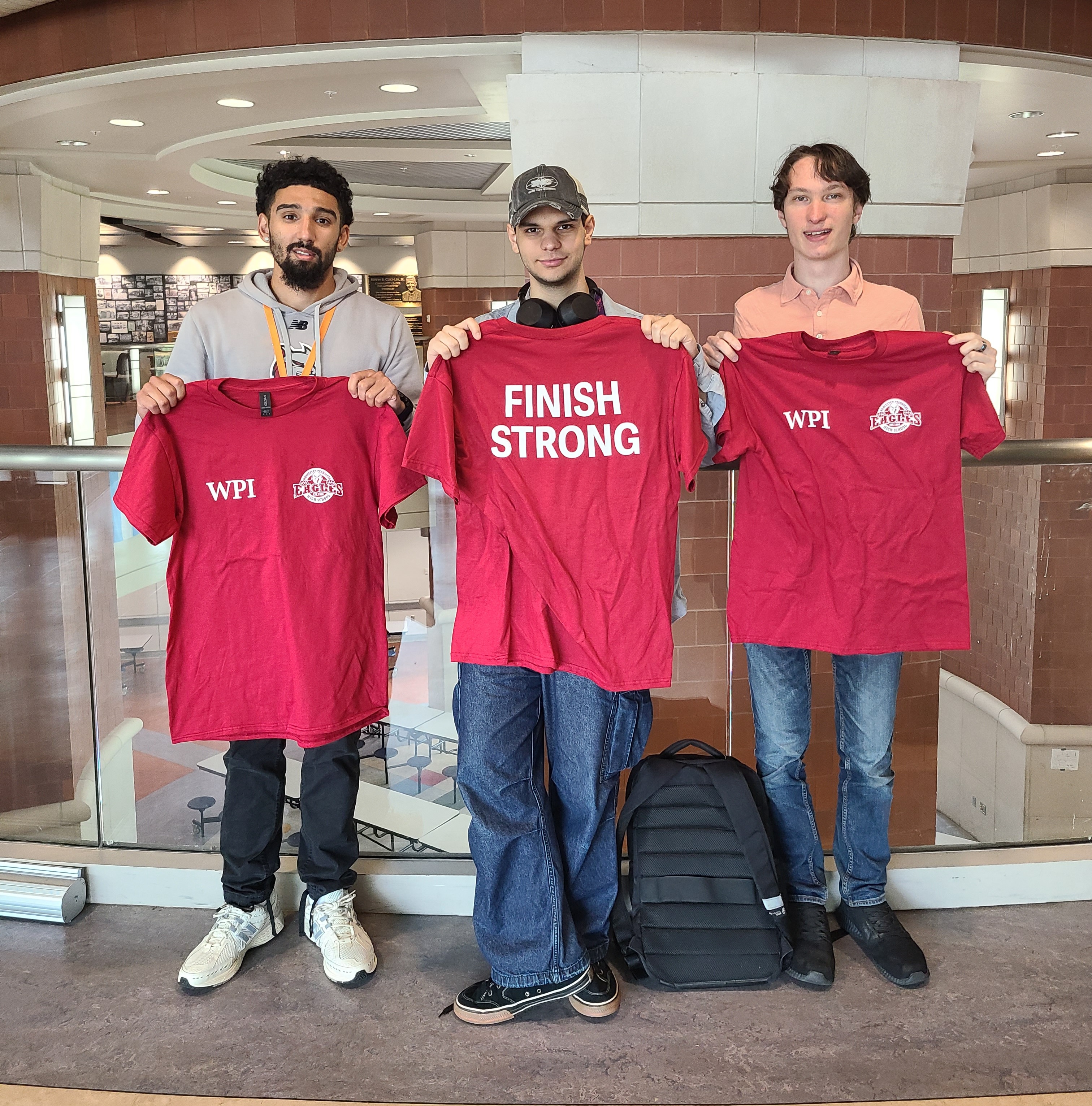 WPI Students Martin Kalo (middle) and Dashiell Elliot (right) receive a “Finish Strong” T-shirt as a thank you from Worcester Tech High School.  Joining them is Wraparound Coordinator Jason Feliciano (left).
