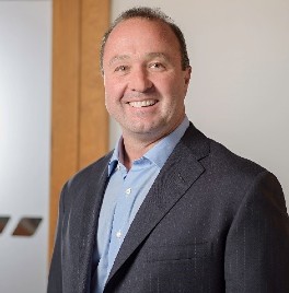 Greg Tucker in button down shirt and suit jacket