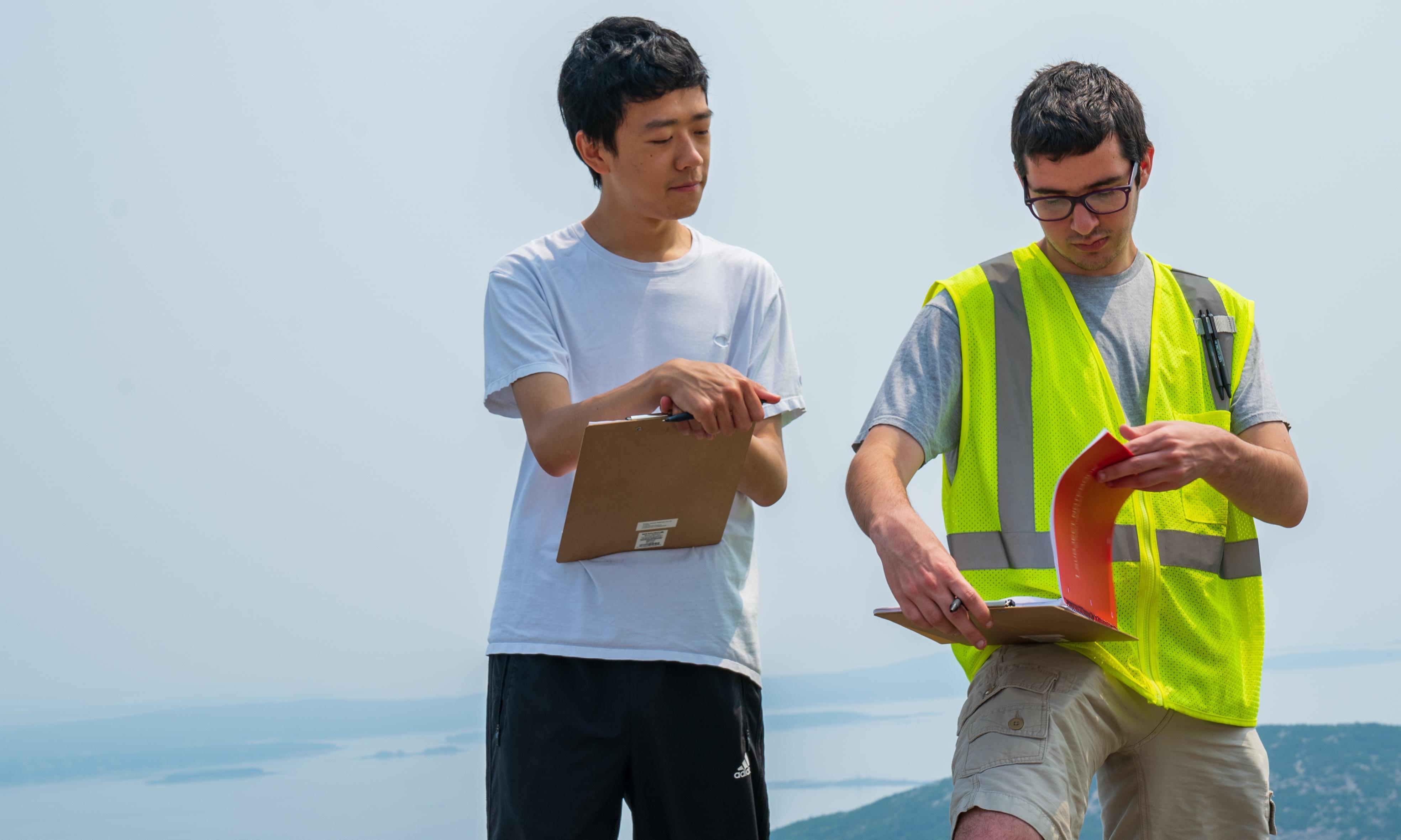 Two WPI Students standing with clipboards on a mountain