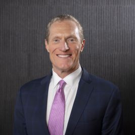 Woody Bradford wearing a suit and tie and white button down shirt