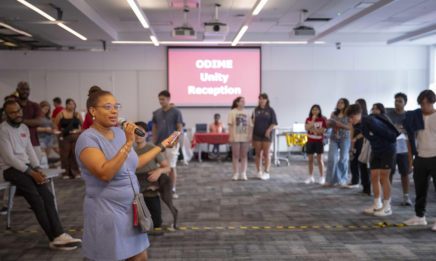 Woman of color holding a microphone at a WPI ODIME event