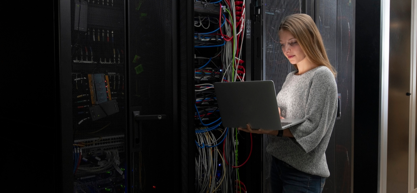 Student with laptop standing in server room