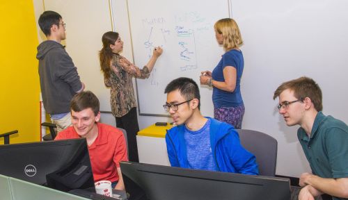 students working at white board and at computer desk