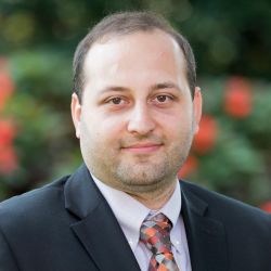 Seyed Niknam of Western New England University appears in a suit against a green background.