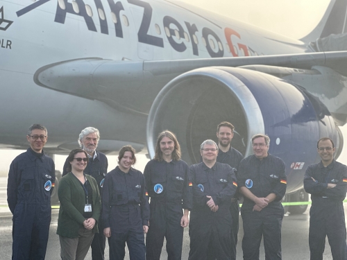 Group of researchers standing in front of jumbo jet, smiling