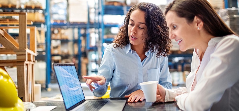 Two women working on a laptop in a warehouse