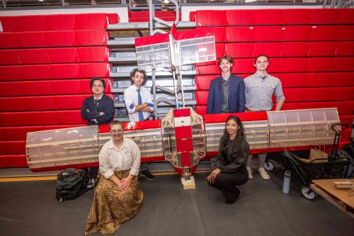 students pose with glider plane