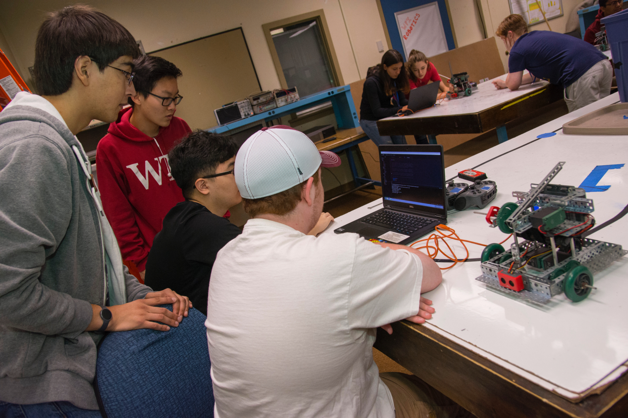 Group of students surrounding a laptop and working actively.