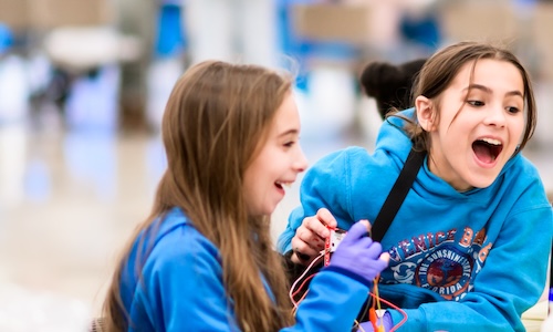 Two middle-school-aged girls showing excitement as they participate in a hands-on activity at WPI.