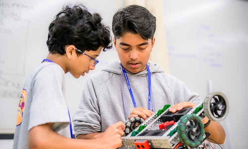 Two high school students engaged in a hands-on STEM activity during WPI's Launch summer program, building a small mechanical vehicle.