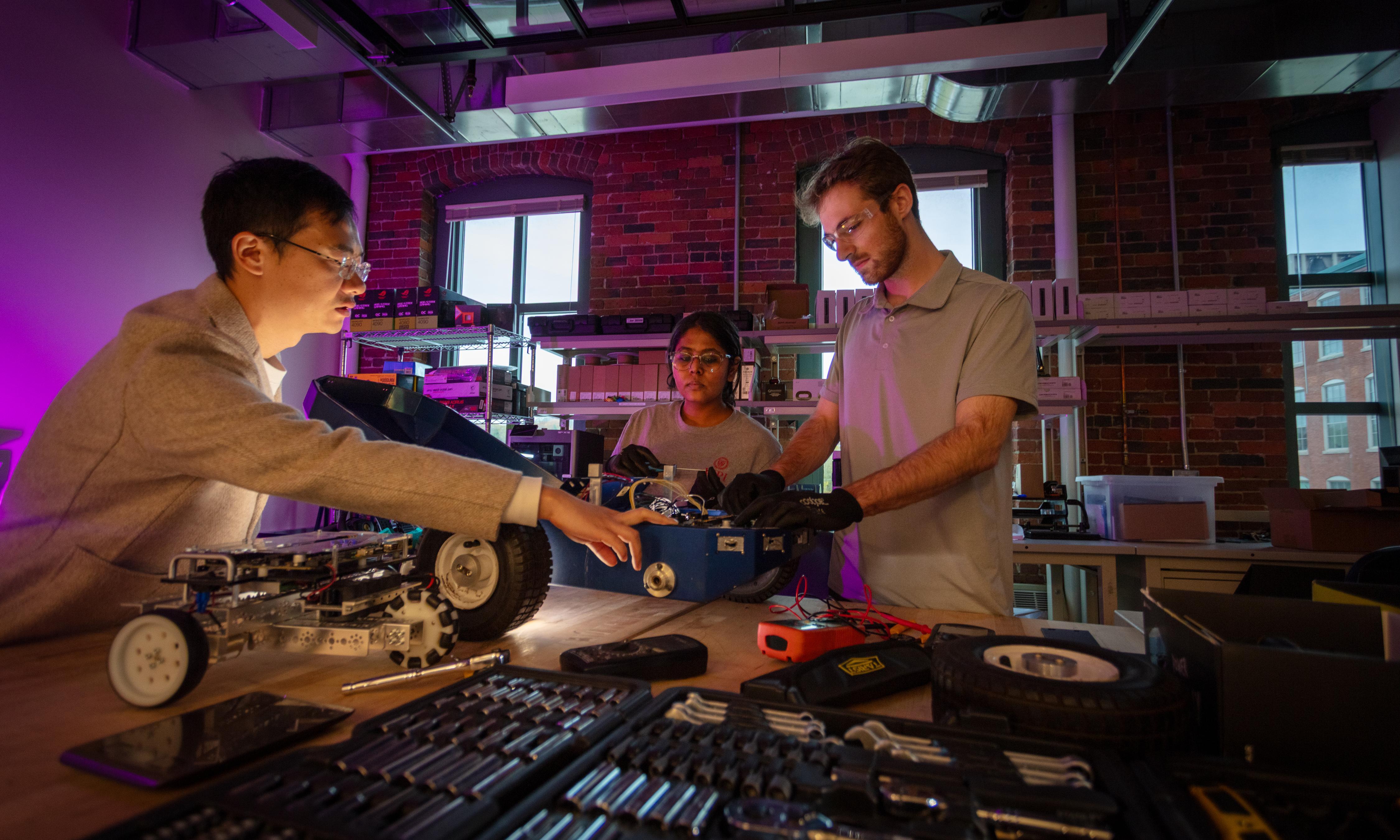 WPI undergrad students and their professor working on an autonomous vehicle