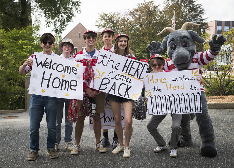 Student Alumni Society members hold welcome home signs for alumni