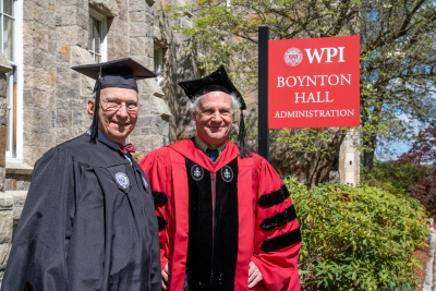 Student in cap and gown standing next to professor in academic regalia