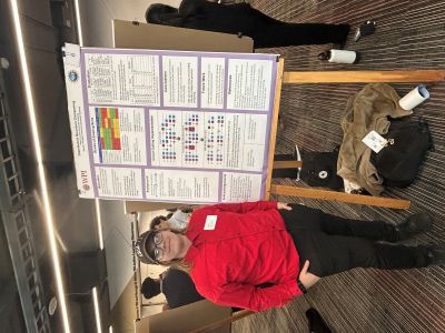 male student in red shirt standing next to poster