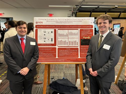 2 male students in front of red poster