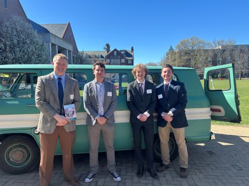 four students in front of light green van