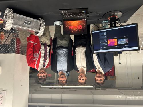 students in front of table with video screen and small robot with wheels