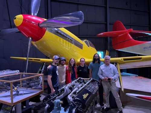 students at air museum posing in front of yellow plane