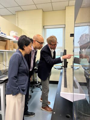 Taylor, Dempski, Wang in lab looking at piece of equipment