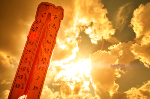 thermometer showing a high temperature, seen in front of an orange summer sky