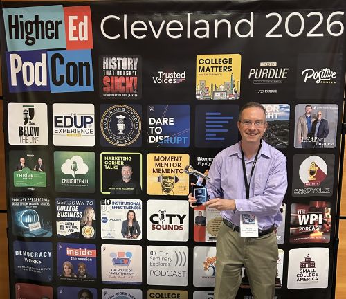 Jon Cain holds podcast trophy standing in front of step and repeat