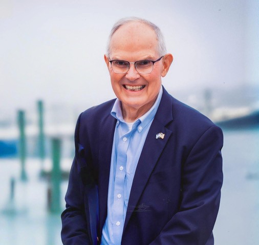 Man in a blue suit in front of a harbor