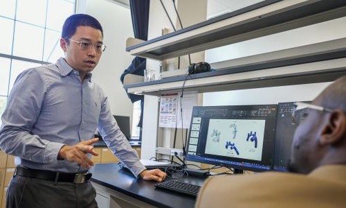 Man wearing eyeglasses talks in a laboratory.