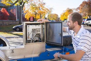 PhD student Ryan Worsman checks ethernet cables connected from the falling weight deflectometer to an on-board computer.