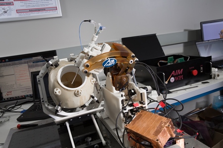 A closer view  of the prototype robot (at center) guiding the ultrasound probe. The black box at right is the modular controller for the robot.
