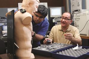 Kaveh Pahlavan, right, and graduate student Umair Khan attach sensors to a mannequin used to study body area networks.
