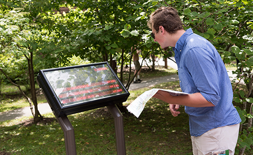 Student team member Jackson Peters investigates the electronic scheduling bus sign at the Nature Center