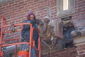 A worker prepares to lower one of the limestone grotesques from the rear of Alumni Gym.
