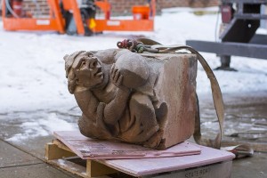 Once safely down, the grotesque rests on a wooden pallet while workers inspect and measure it.