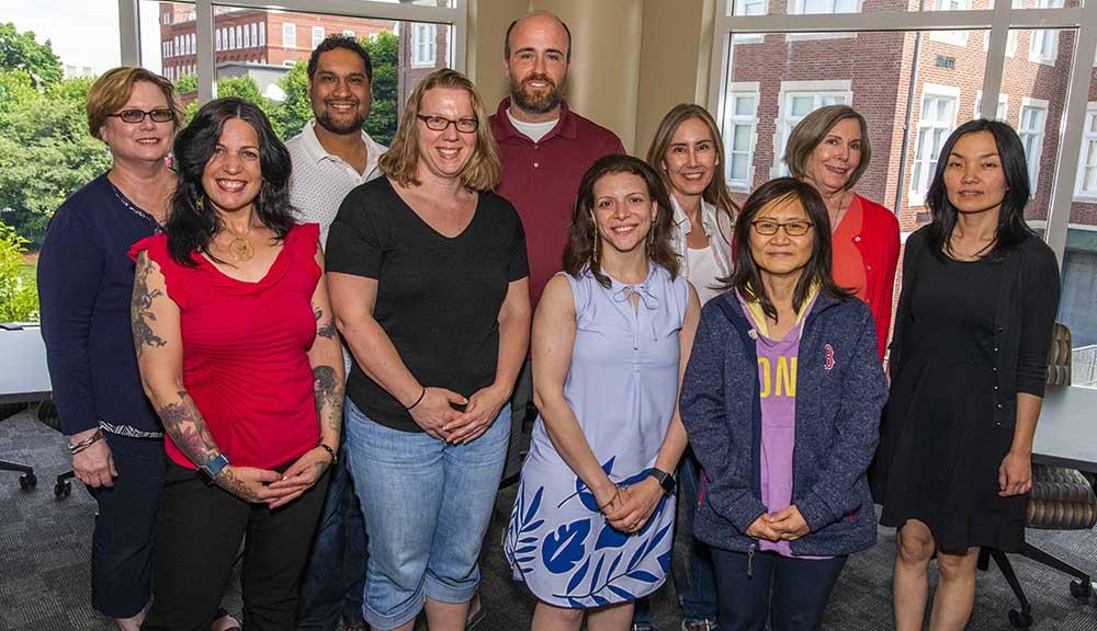 A group photo of the IPBL team that attended this year's Institute on Project-Based Learning. They're all wearing casual clothing, and are standing in front of large windows in the Rubin Campus Center.
