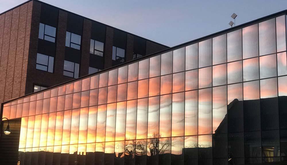 An exterior shot of the sunset shining against the Foisie Innovation Studio.
