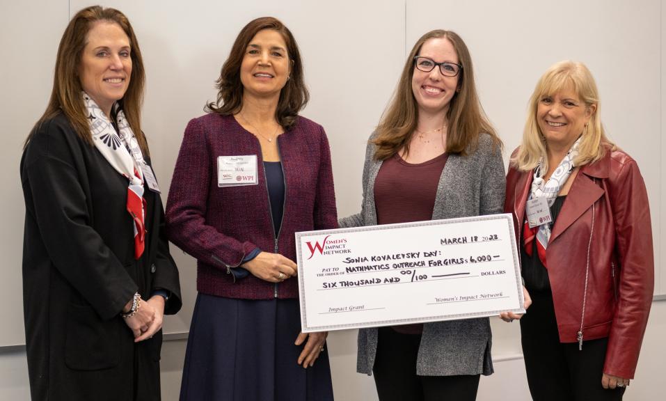 four women pose with large check