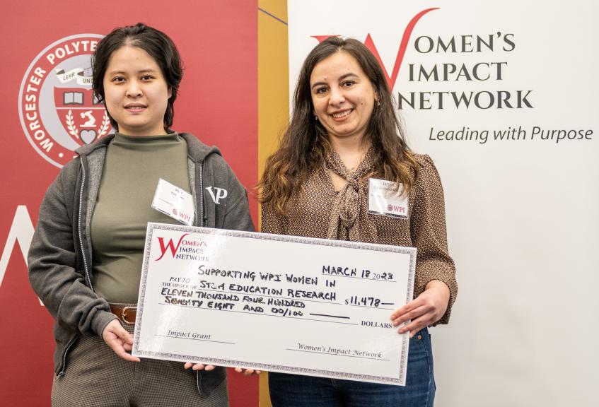 two women pose with large check