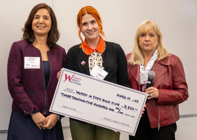 three women pose with large check