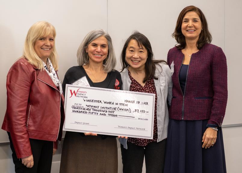 four women pose with large check