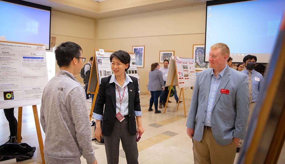 Grace Wang visits researchers in the Odeum during their GRIE presentations.
