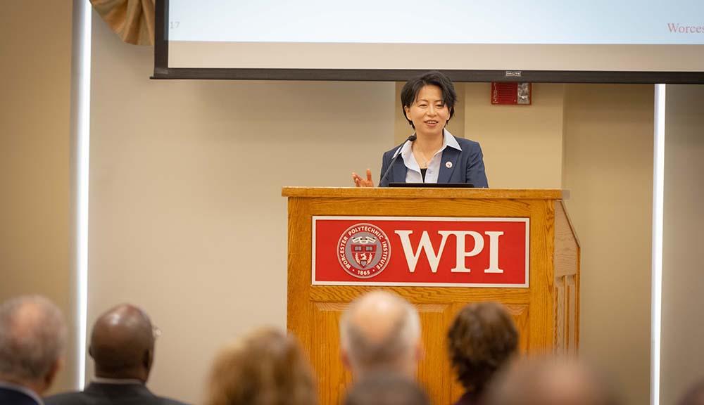 Grace Wang addresses faculty and staff at the podium.