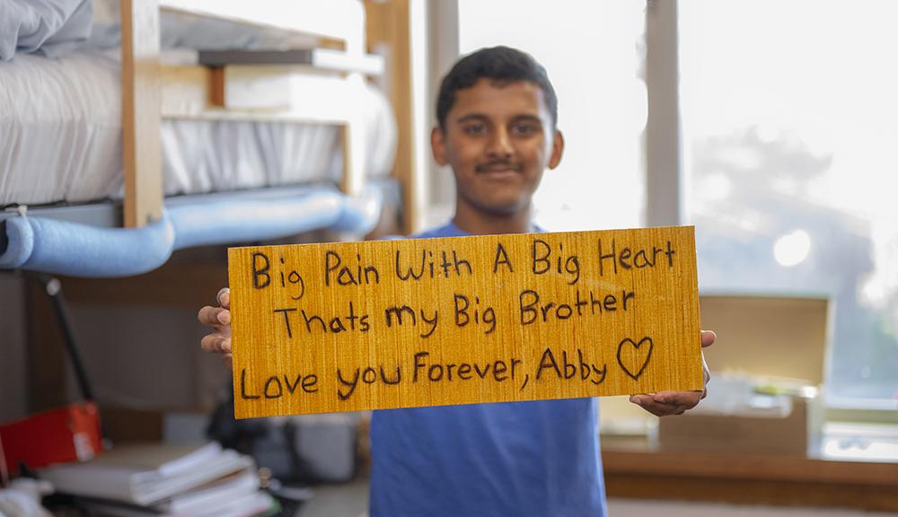Ethan shows a sign that reads: Big Pain with a Big Heart. That's my big brother. Love you forever. Abby