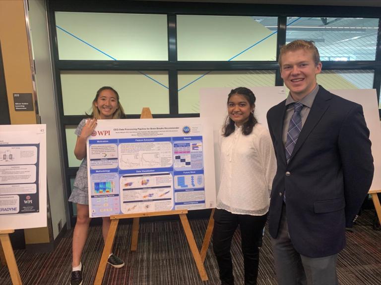 A photo of several students in front of the project poster board summer 2022