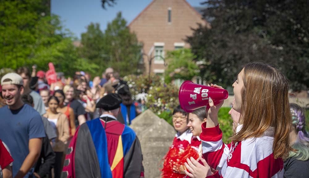 A student cheers as new students cross Earle Bridge.