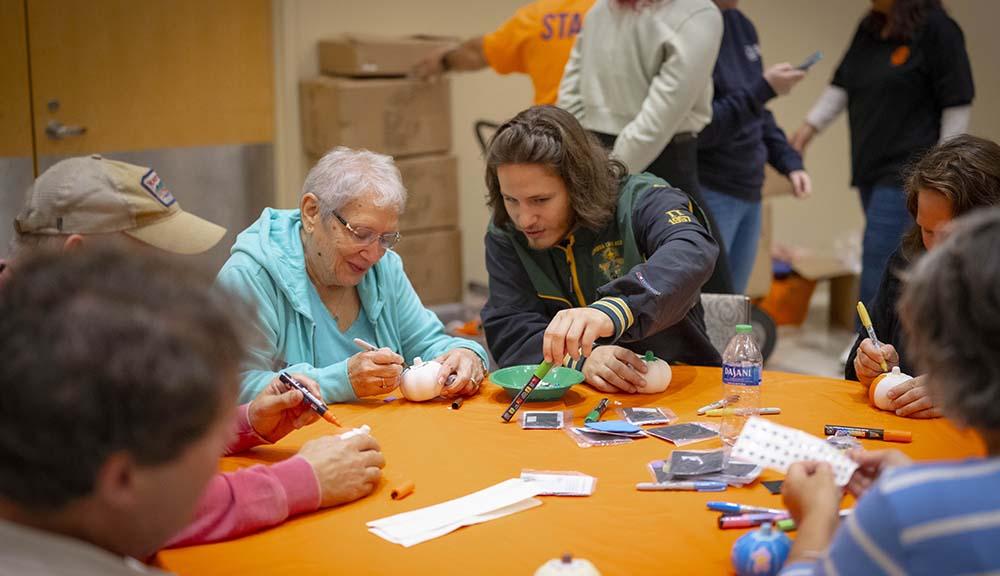Family members paint pumpkins as part of Family Weekend activities.